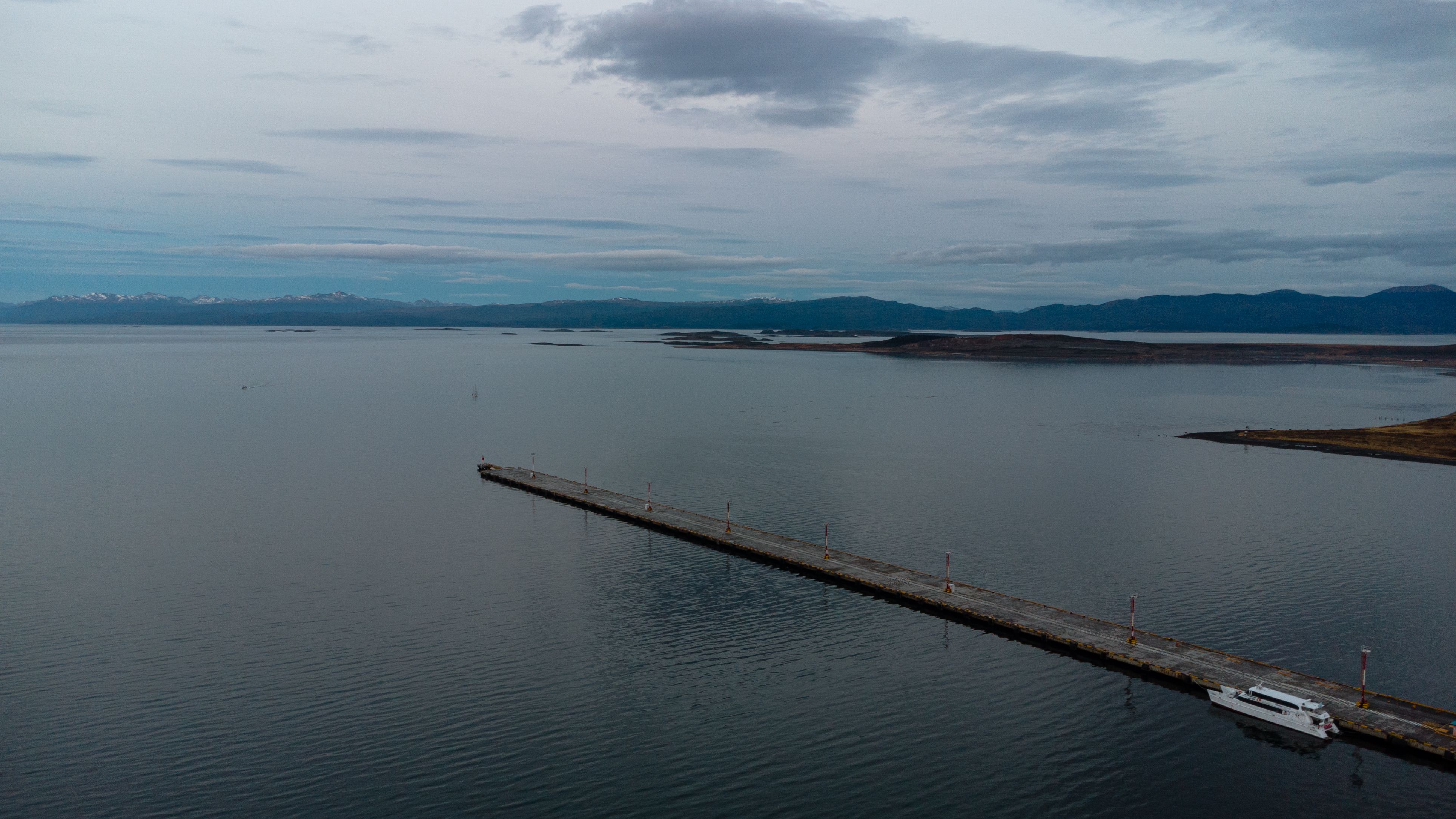 Unbeatable Private Helicopter Tour Review: Soaring Above Buenos Aires and the Paraná Delta Review 2026 - Scenic aerial shot of the Ushuaia pier during twilight, with calm waters and distant mountains.