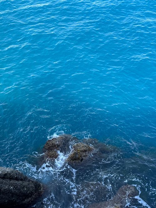 Free A beautiful view of turquoise sea waters splashing against rocks in Portofino, Liguria. Stock Photo