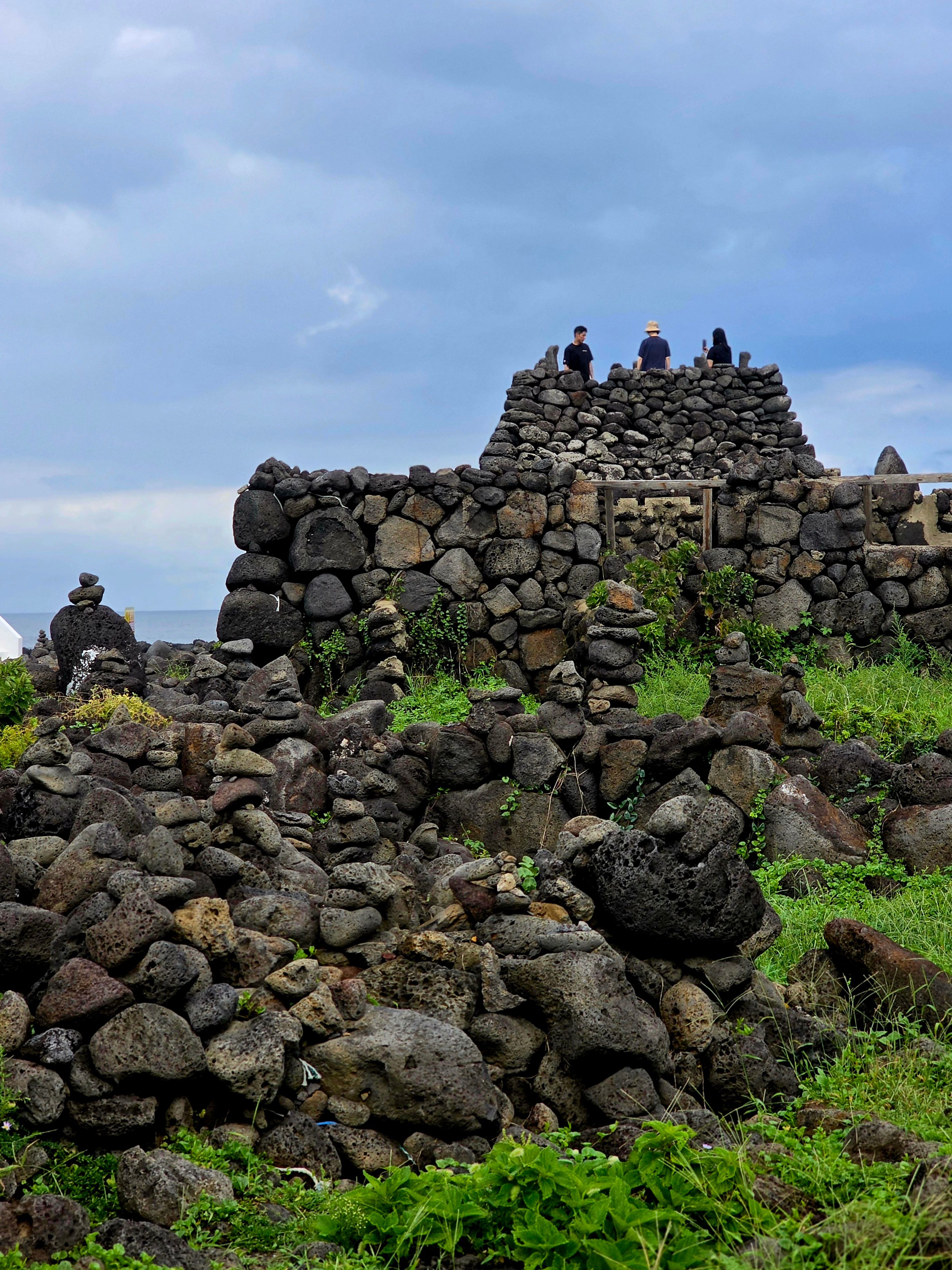 Explore historic stone structures amidst lush greenery on Jeju Island, South Korea.