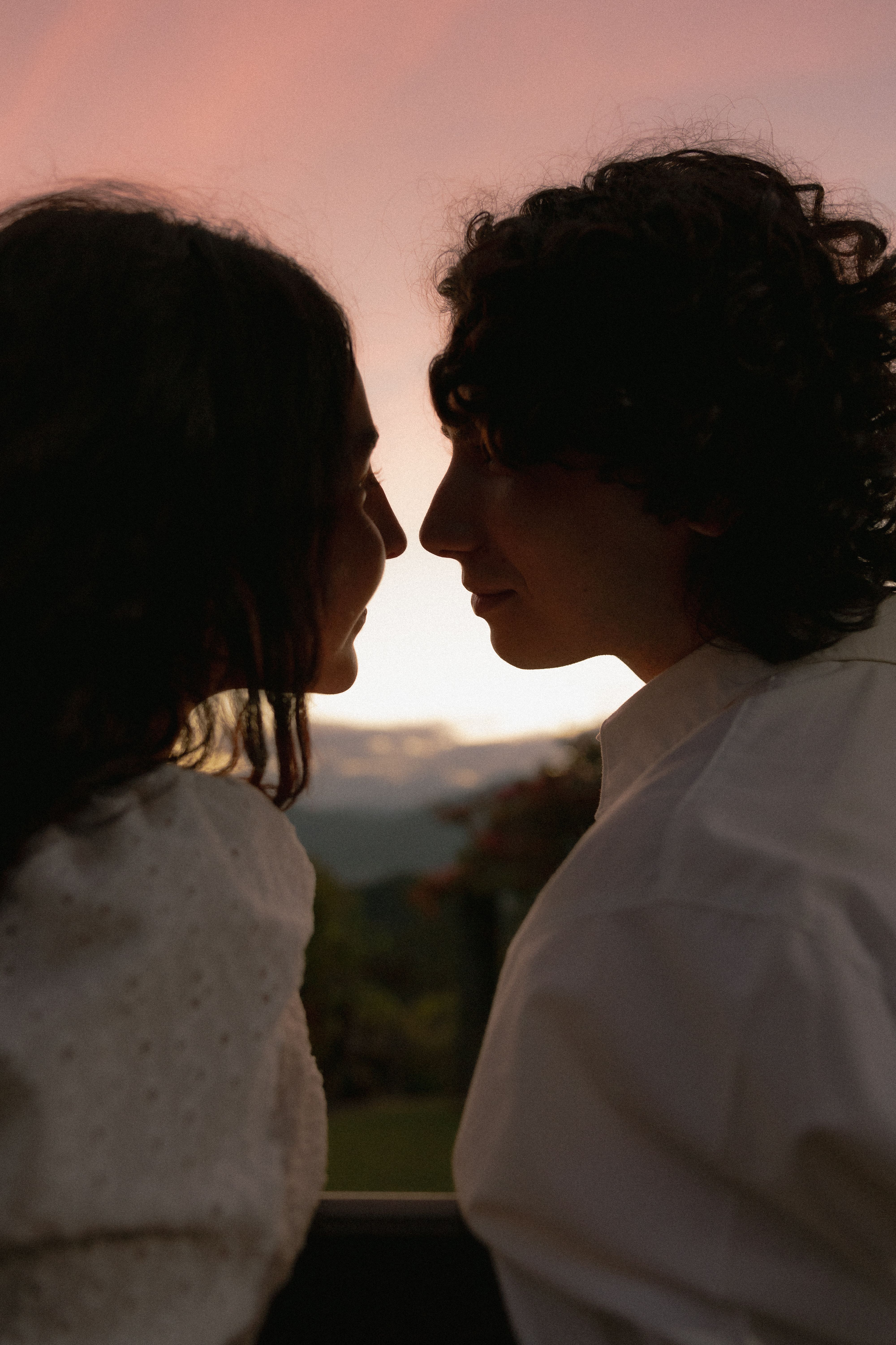 A silhouette of a couple gazing at each other tenderly during a stunning sunset.
