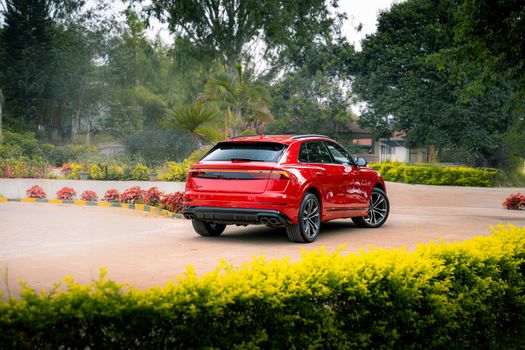 Vibrant red SUV showcased in a lush garden, perfect for automotive enthusiasts.