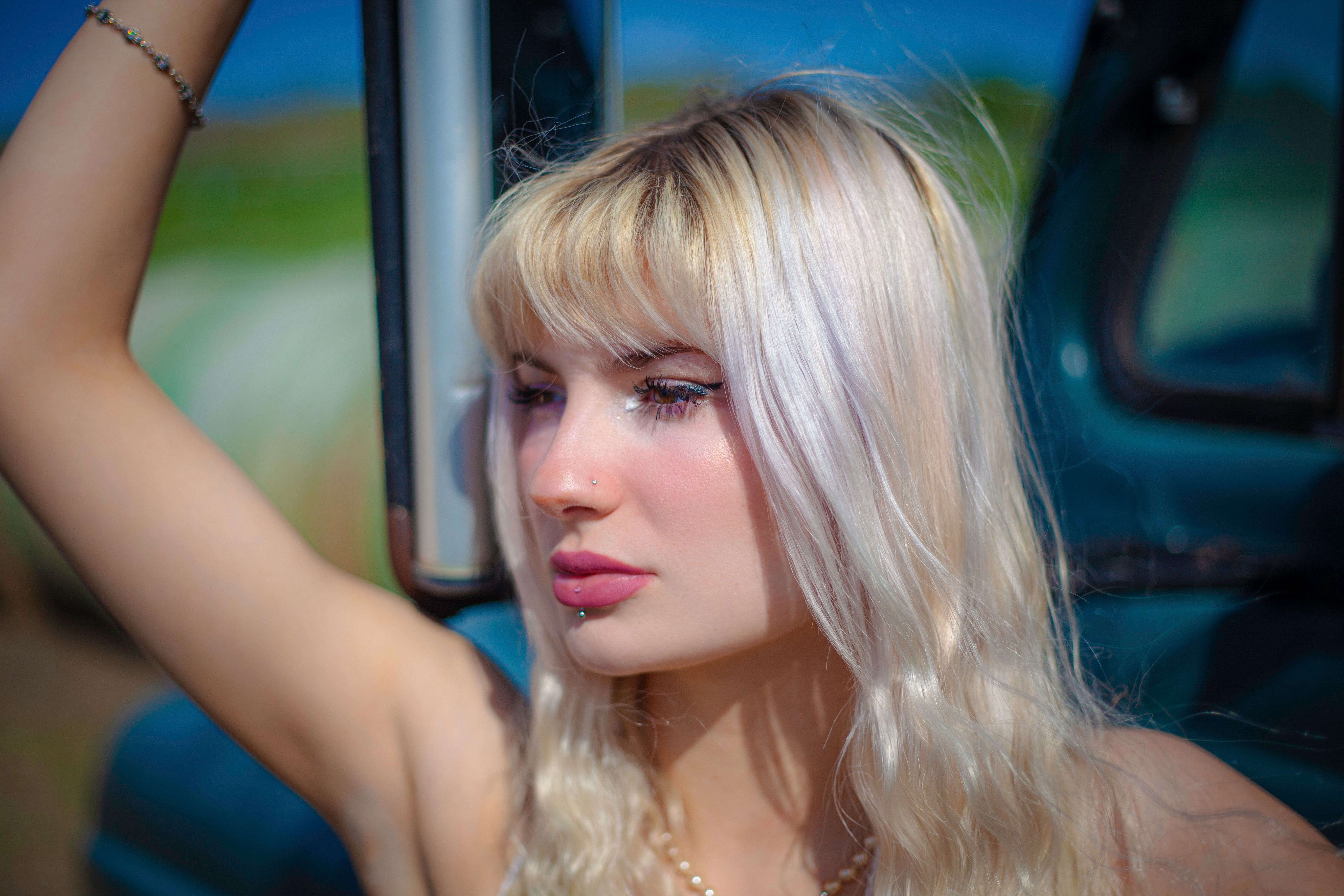 A young blonde woman posing confidently outdoors with a serene expression.