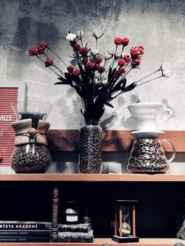 Stylish shelf arrangement of coffee beans and red roses for a cozy interior ambiance.