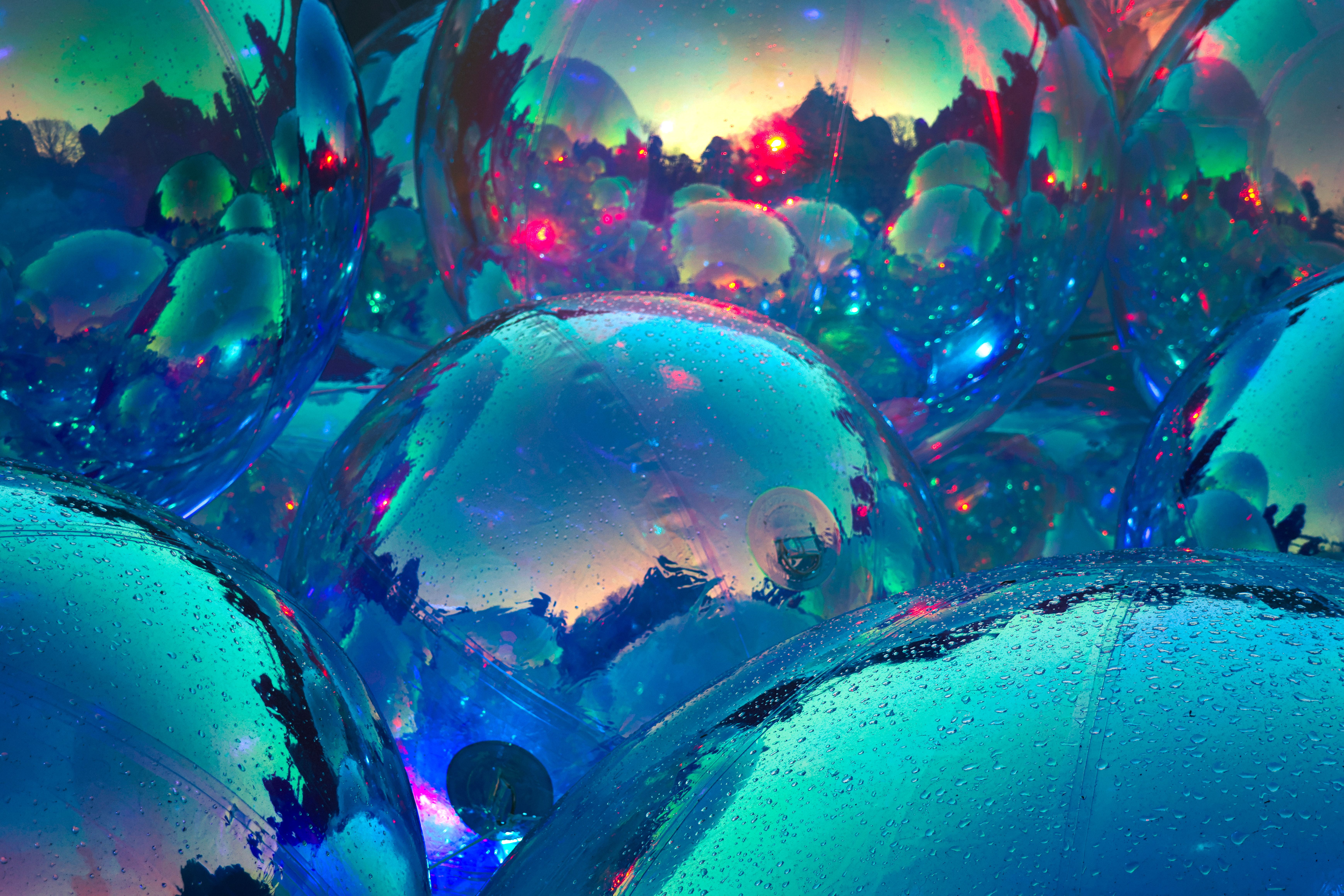 Colorful reflective spheres with water droplets, showcasing a vivid, abstract play of colors in an artistic display.