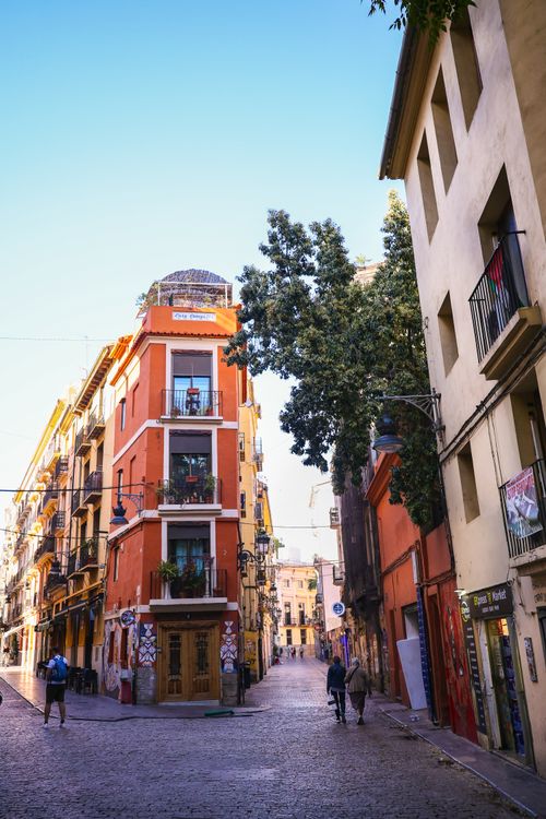 Free Explore a vibrant street in Valencia, Spain, lined with colorful historic buildings under a clear blue sky. Stock Photo