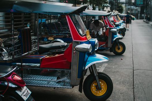 Colorful tuk tuks parked in a row on an urban street, emphasizing transportation culture.