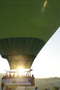 Hot air balloon ride at sunrise in Cappadocia, Turkey with sun peeking through.