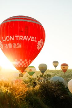 Colorful hot air balloons rise over scenic Cappadocia at sunrise, creating a picturesque view.