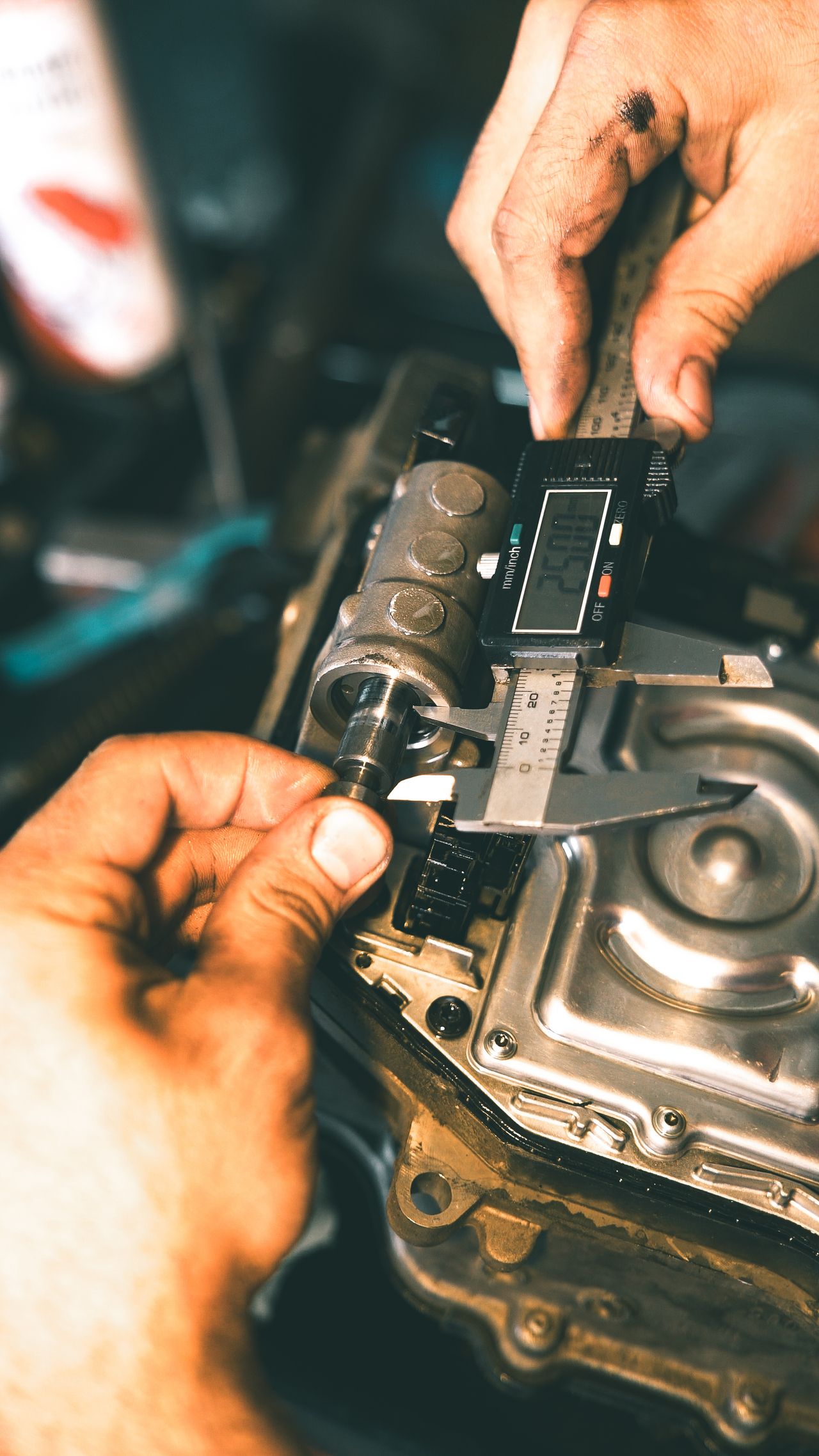 Mechanic using a digital caliper for precise measurement of metal component