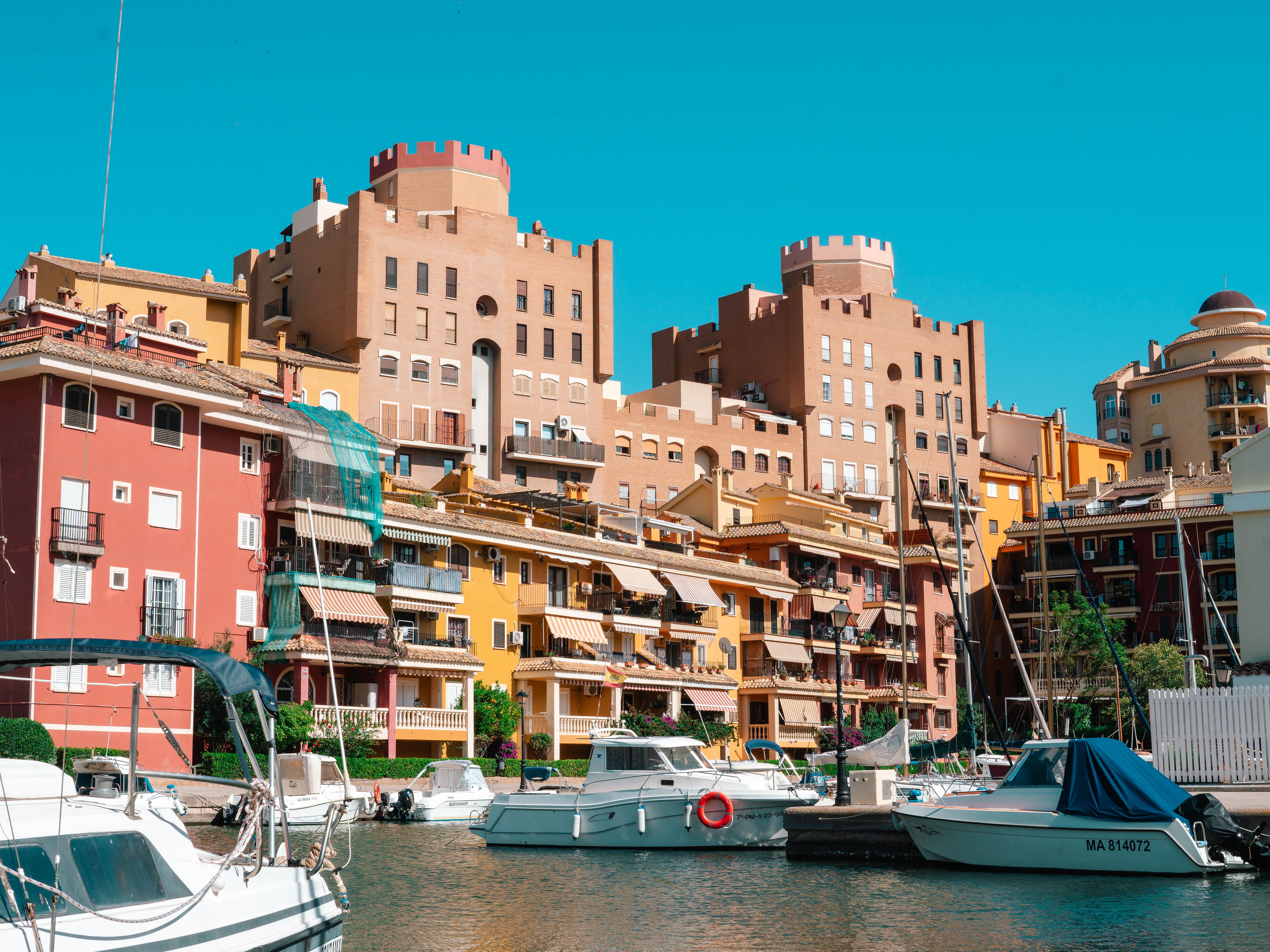 Vibrant architectural scene with boats at Port Saplaya Marina, Valencia, Spain.