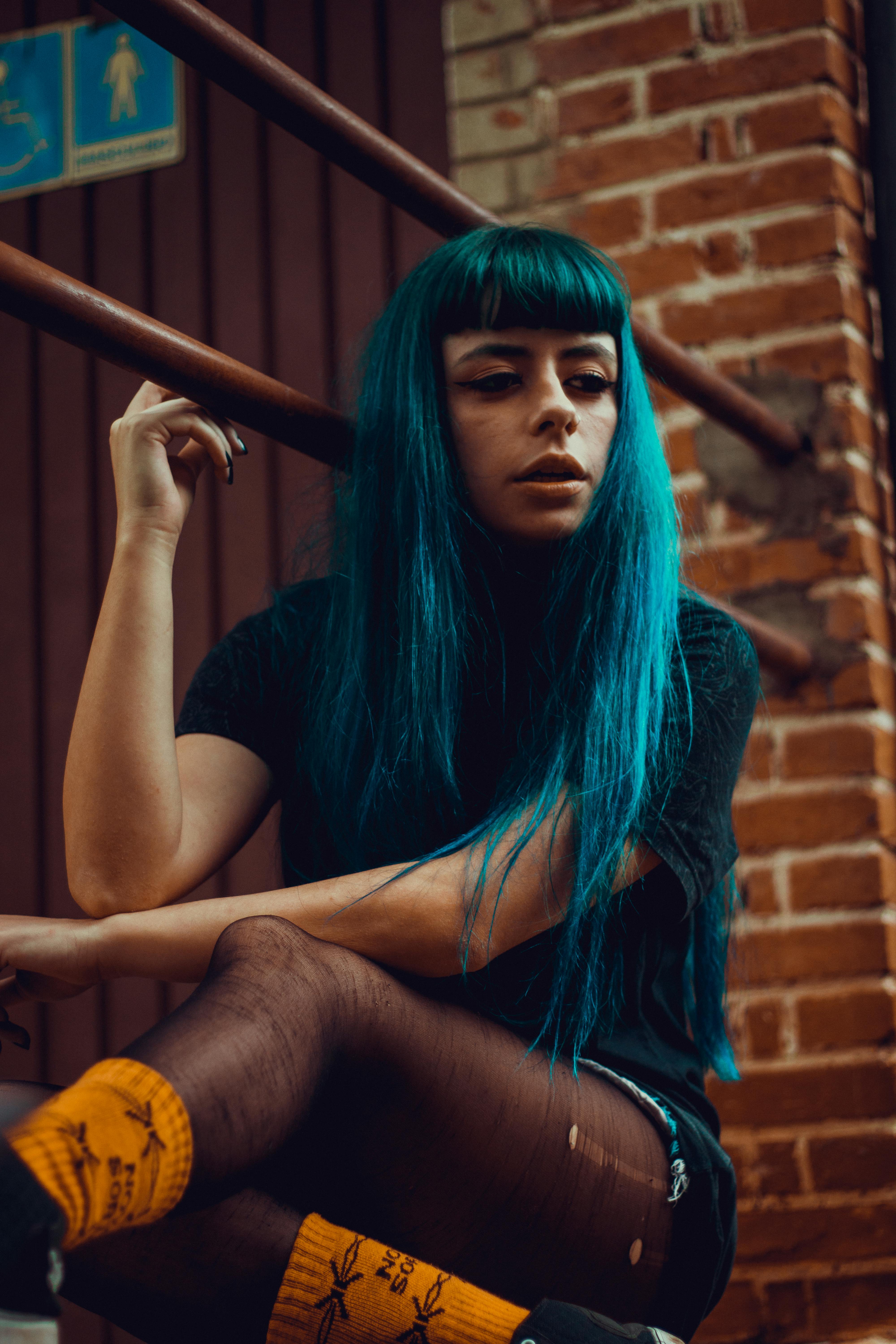 blue haired woman resting on staircase