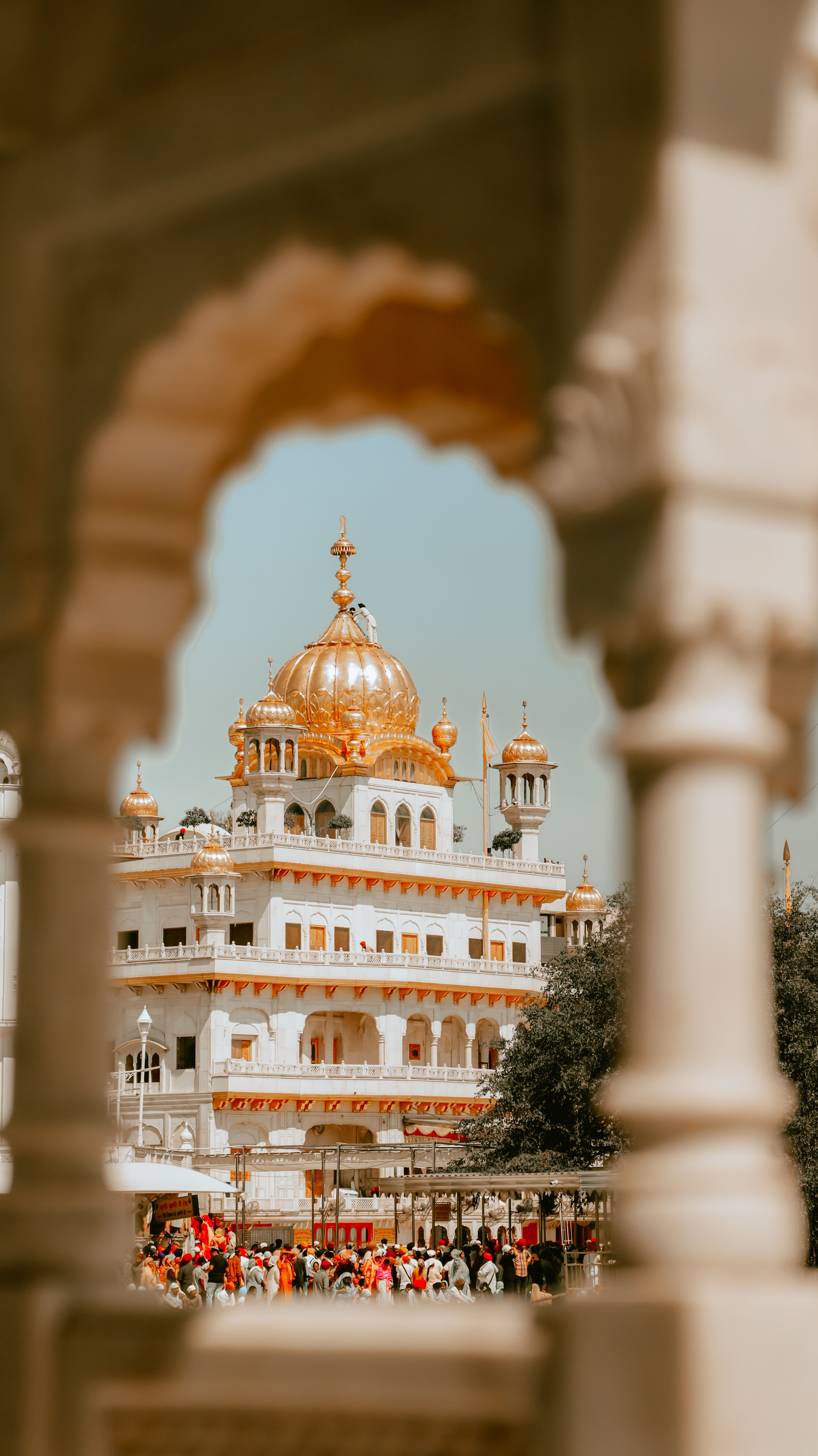 The Golden Temple in Amritsar framed by an ornate archway on a sunny day.