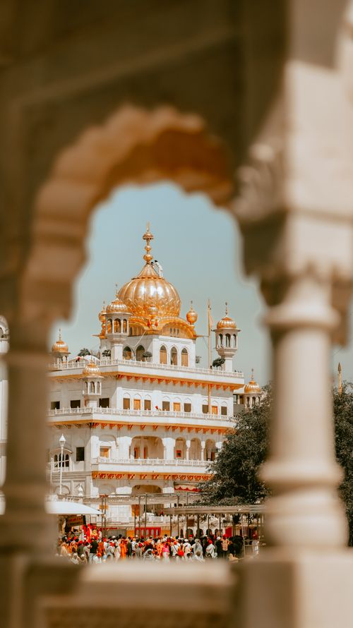 Free The Golden Temple in Amritsar framed by an ornate archway on a sunny day. Stock Photo