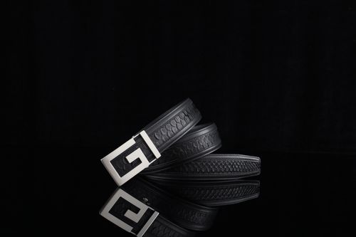 Free Chic black leather belt with a stylish metallic buckle reflecting on a black surface. Stock Photo
