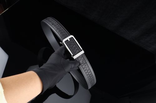 Free A black leather belt featuring a silver buckle held by a gloved hand. Stock Photo