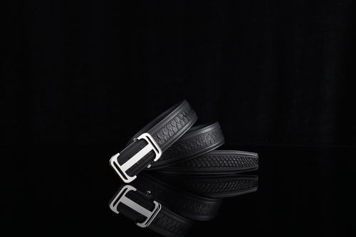 Free Stylish black leather belt with metallic buckle, displayed on a glossy black surface. Stock Photo