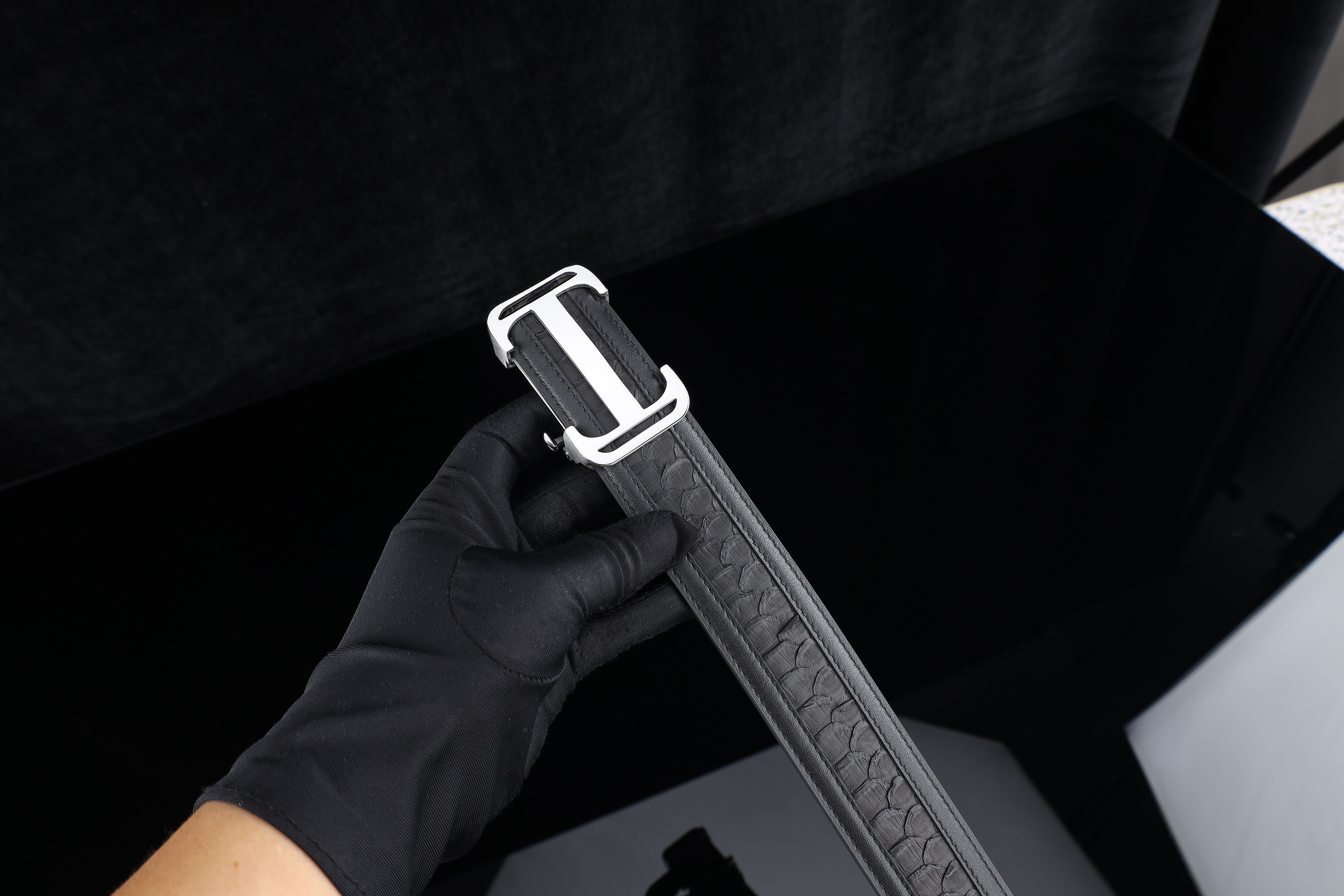 A minimalist close-up of a professional inspecting a rare luxury item with precision tools in a studio setting.
