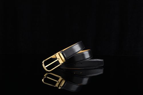 Free Sophisticated black leather belt with a sleek gold buckle on a reflective surface. Stock Photo