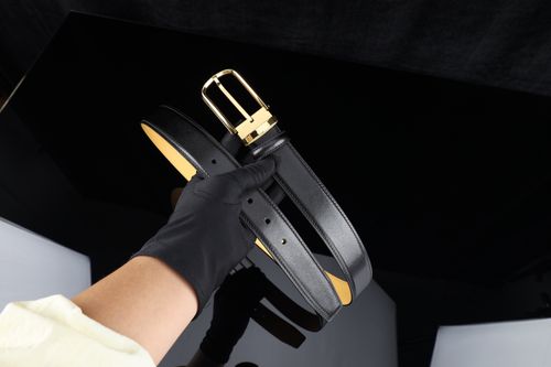 Free Stylish black leather belt with a gold buckle held by a gloved hand, perfect for fashion shoots. Stock Photo