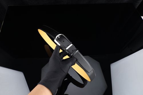 Free Black leather belt held in a studio setting with reflective surfaces and controlled lighting. Stock Photo