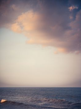 Calm ocean waves under a rich, dramatic sunset sky filled with colorful clouds.