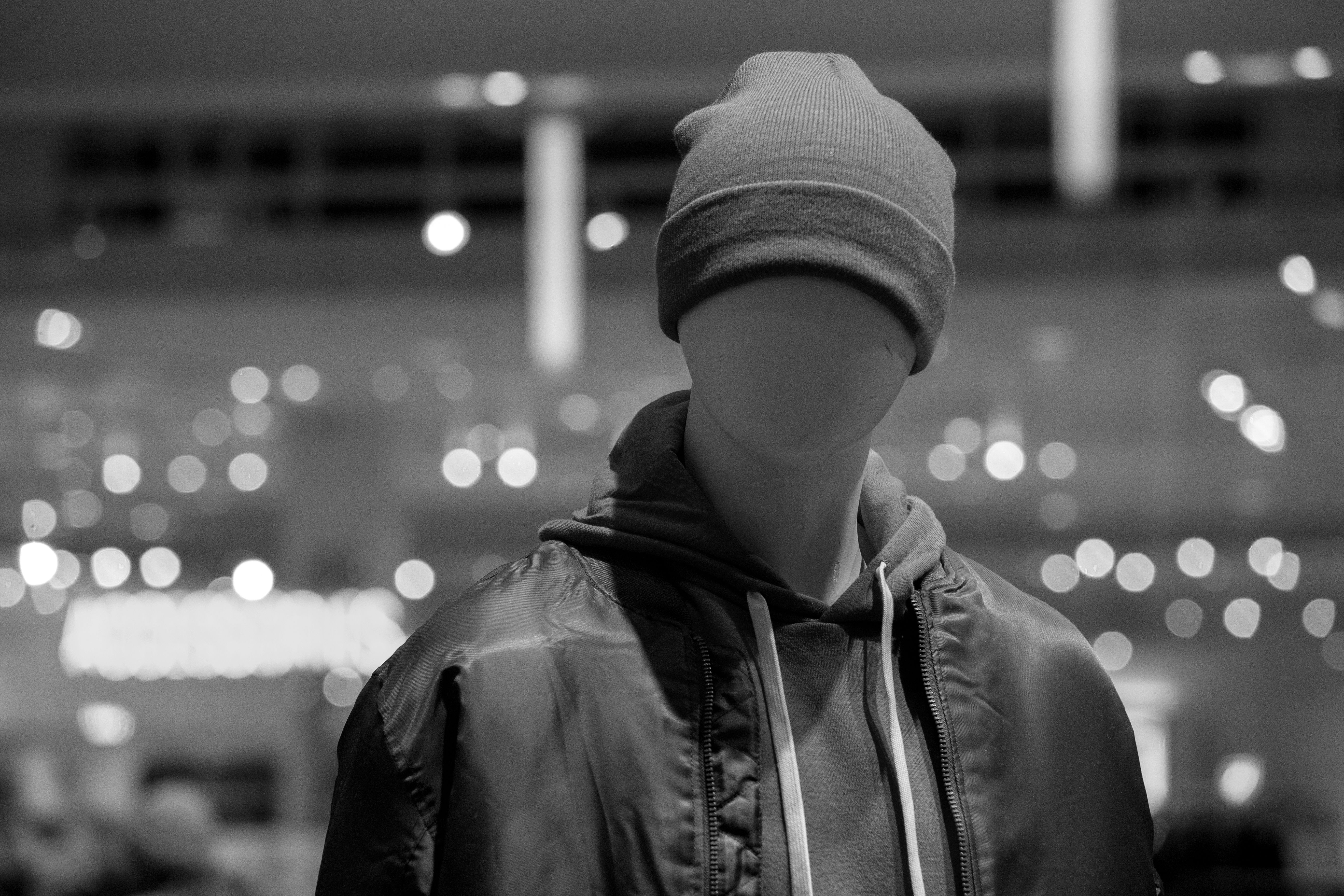 Stylish mannequin wearing a beanie and hoodie in a store setting with bokeh lights.