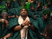 A group of African men wearing green traditional clothing, gathered at an outdoor event.