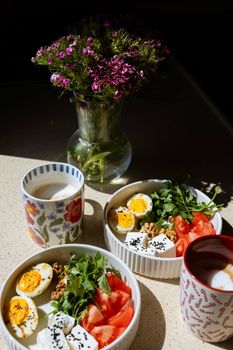 Charming breakfast setup with eggs, veggies, and coffee served with blooming flowers.