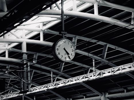 A striking black and white image of a metro station in Dhaka featuring an analog clock, highlighting urban architecture.