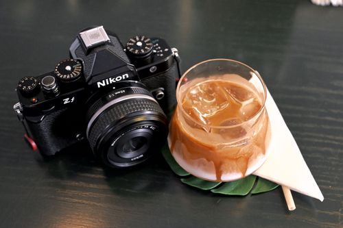 Free Nikon camera and iced coffee drink with napkin on a table. Stock Photo