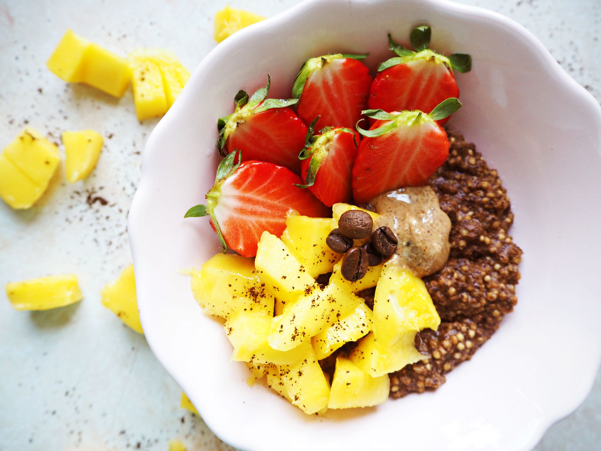 Colorful bowl featuring fresh pineapple, strawberries, and wholesome quinoa topped with coffee beans.