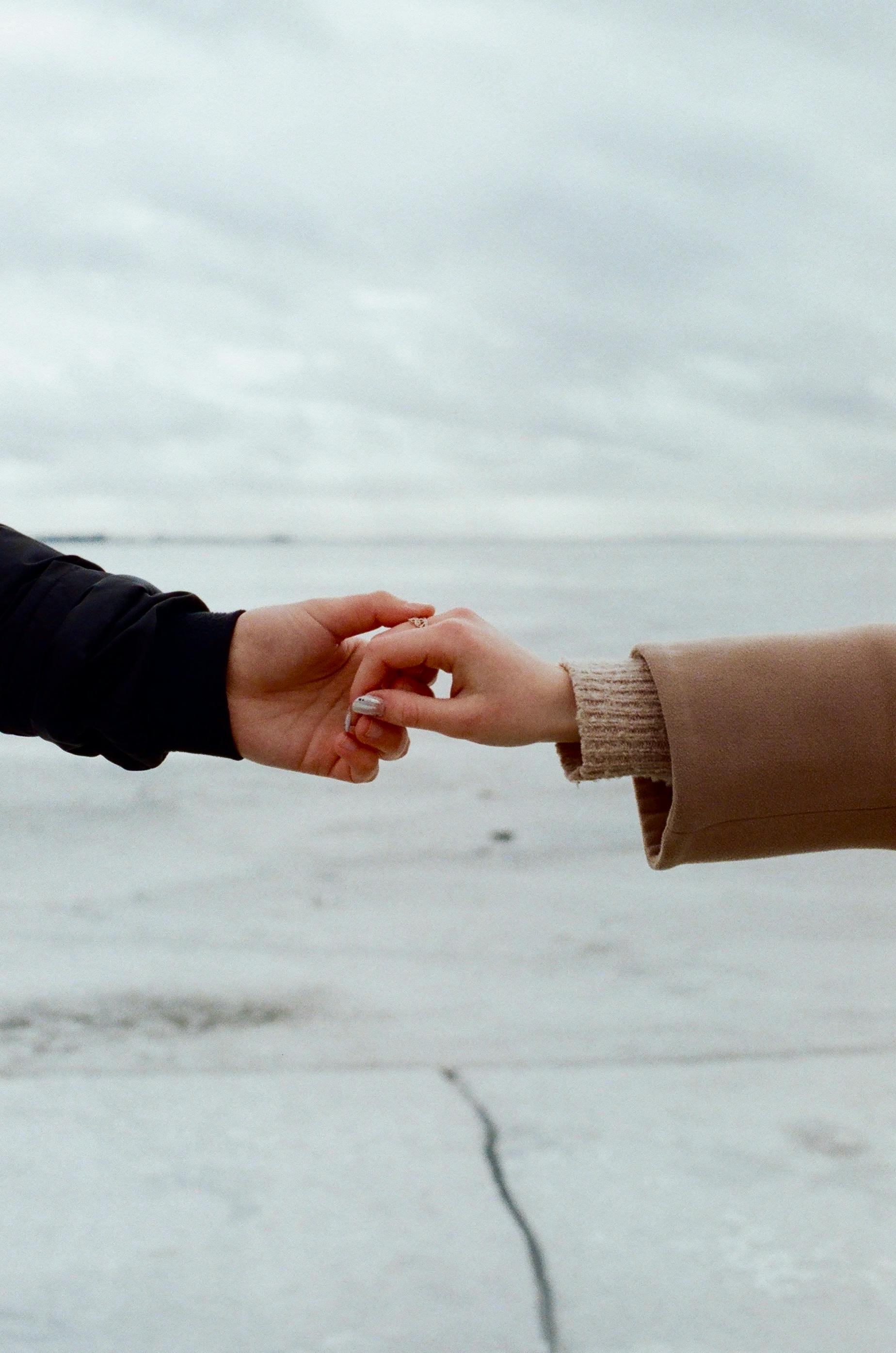 一对夫妇的手轻轻握住白雪皑皑的风景，象征着爱情与联系