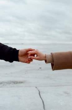 一对夫妇的手轻轻握住白雪皑皑的风景，象征着爱情与联系