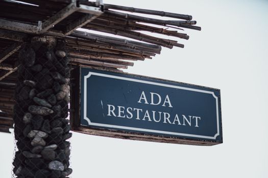 Outdoor sign of Ada Restaurant under a rustic wooden awning in Baku.