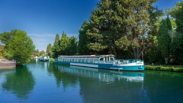 Péniches de plaisance amarrées sur un canal calme sous un ciel bleu