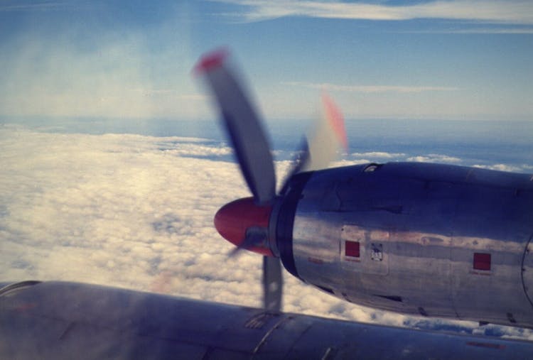 Gray And Red Airplane Flying Under Blue Sky