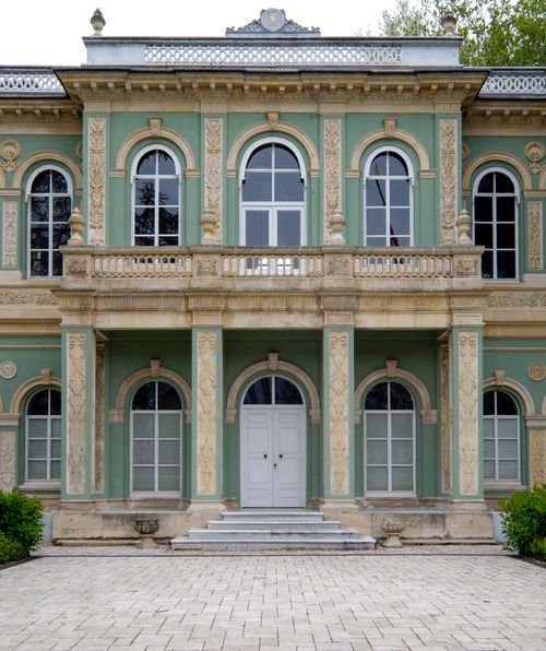 Free Front view of a historic neoclassical building with intricate details and green facade. Stock Photo