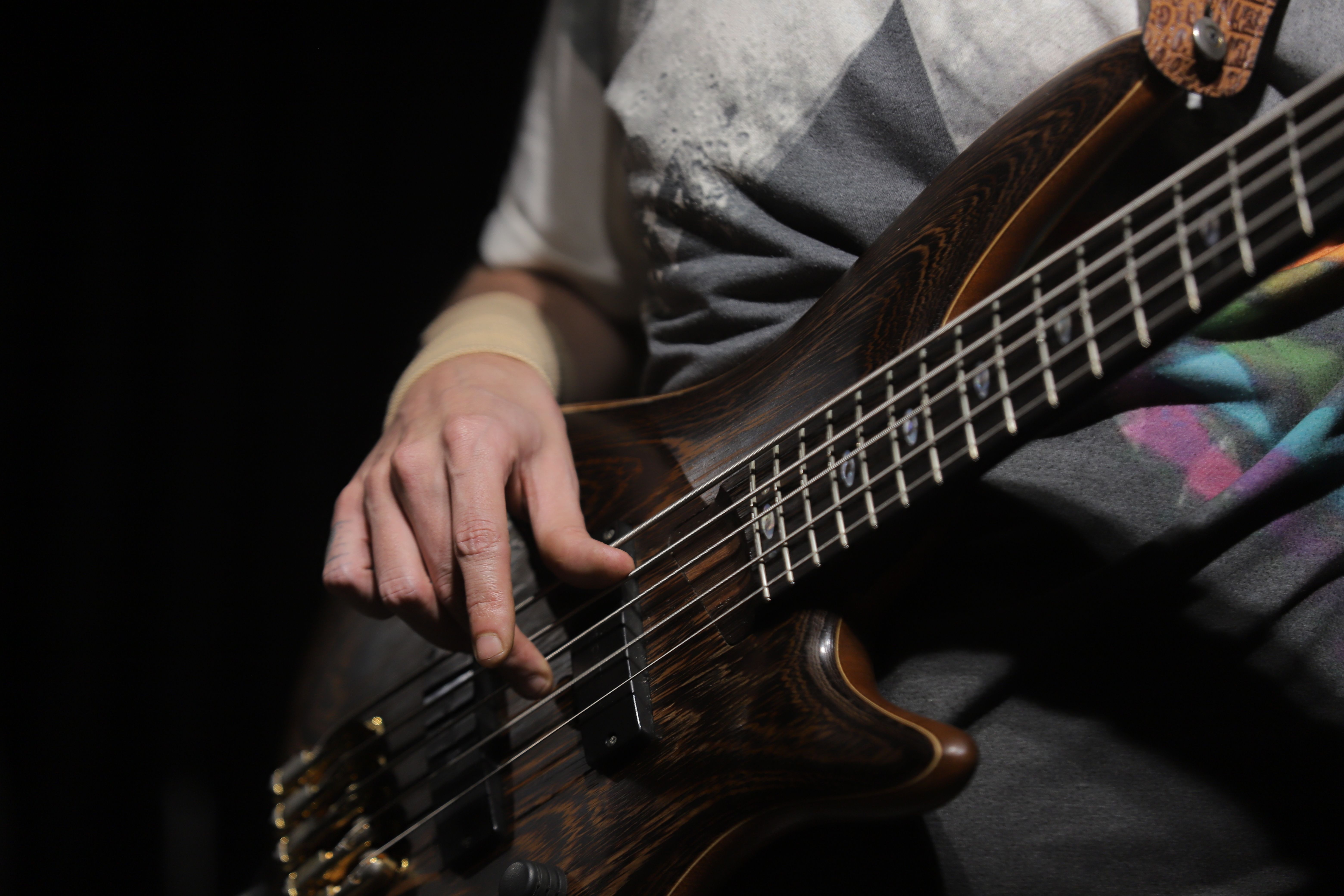 A musician's hands playing bass guitar during an indoor studio music session under stage lighting.. pexels, musicians, hands