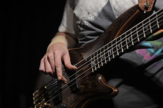 A musician's hands playing bass guitar during an indoor studio music session under stage lighting.. pexels, musicians, hands