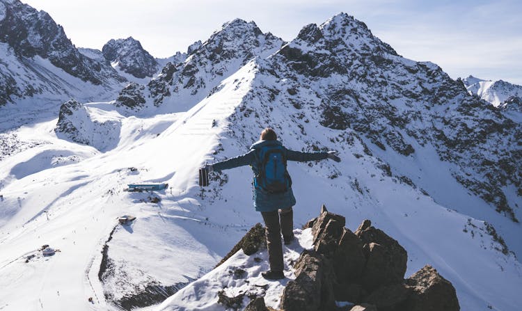 Person Standing On Snow Covered Mountain