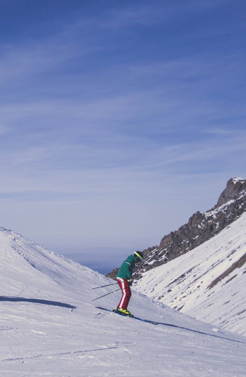 Kostenlos Person In Der Grünen Jacke Und In Der Blauen Hose, Die Auf Schneebedecktem Berg Stehen Stock-Foto