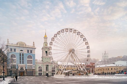 Captivating winter cityscape of the Podil Ferris Wheel and historic architecture in Kyiv, Ukraine.
