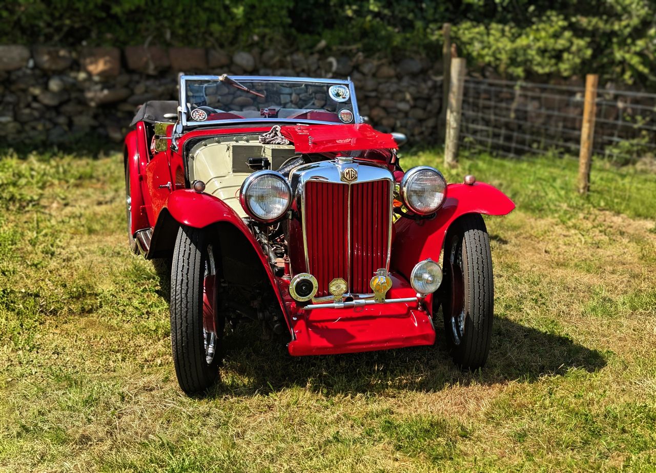 classic red mg sports car parked on grass highlighting its vintage cha