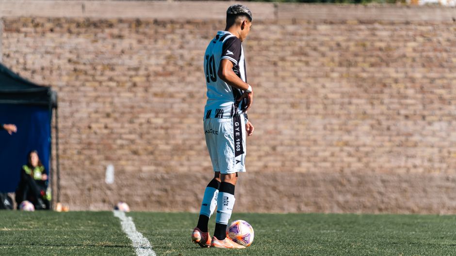 A soccer player in uniform standing on a grass field, ready to take a corner kick.