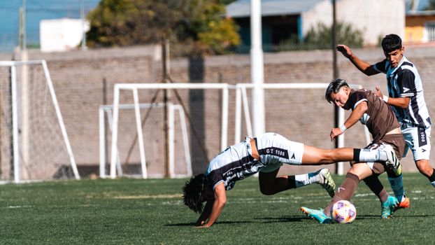 Soccer players in action during a competitive match on a sunny day.