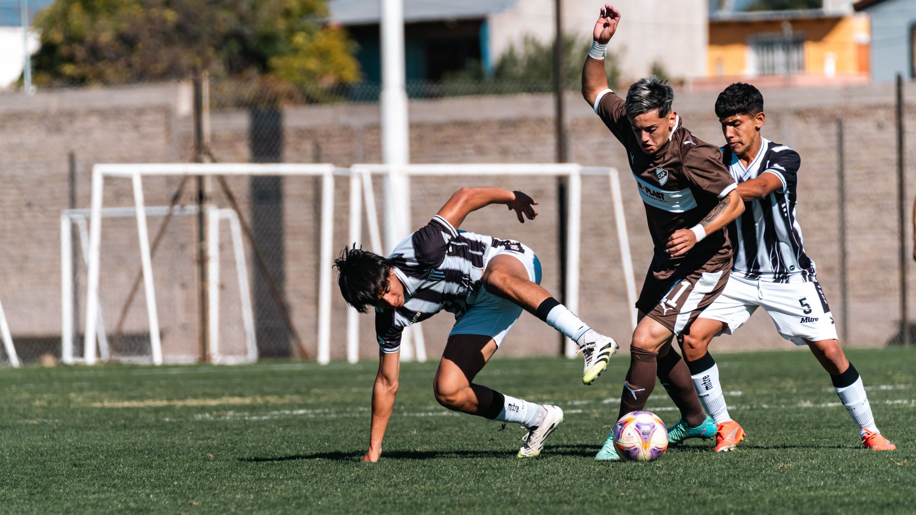 Dramatic moment of soccer match with intense action among three players competing outdoors.