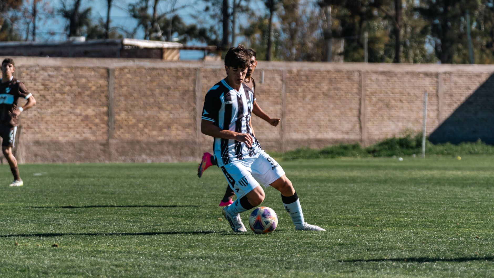 young footballer performing close-control dribbling between cones on a wet training pitch