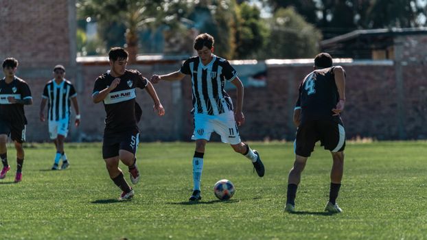Action shot of teenage boys engaged in a competitive soccer game on a sunny day.