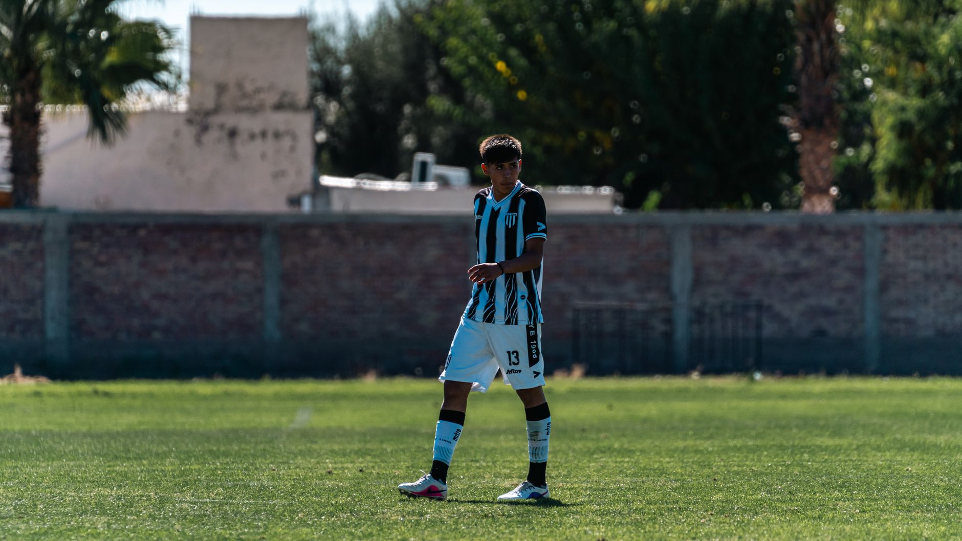 young soccer midfielder practicing close control alone on a wet training pitch at dawn
