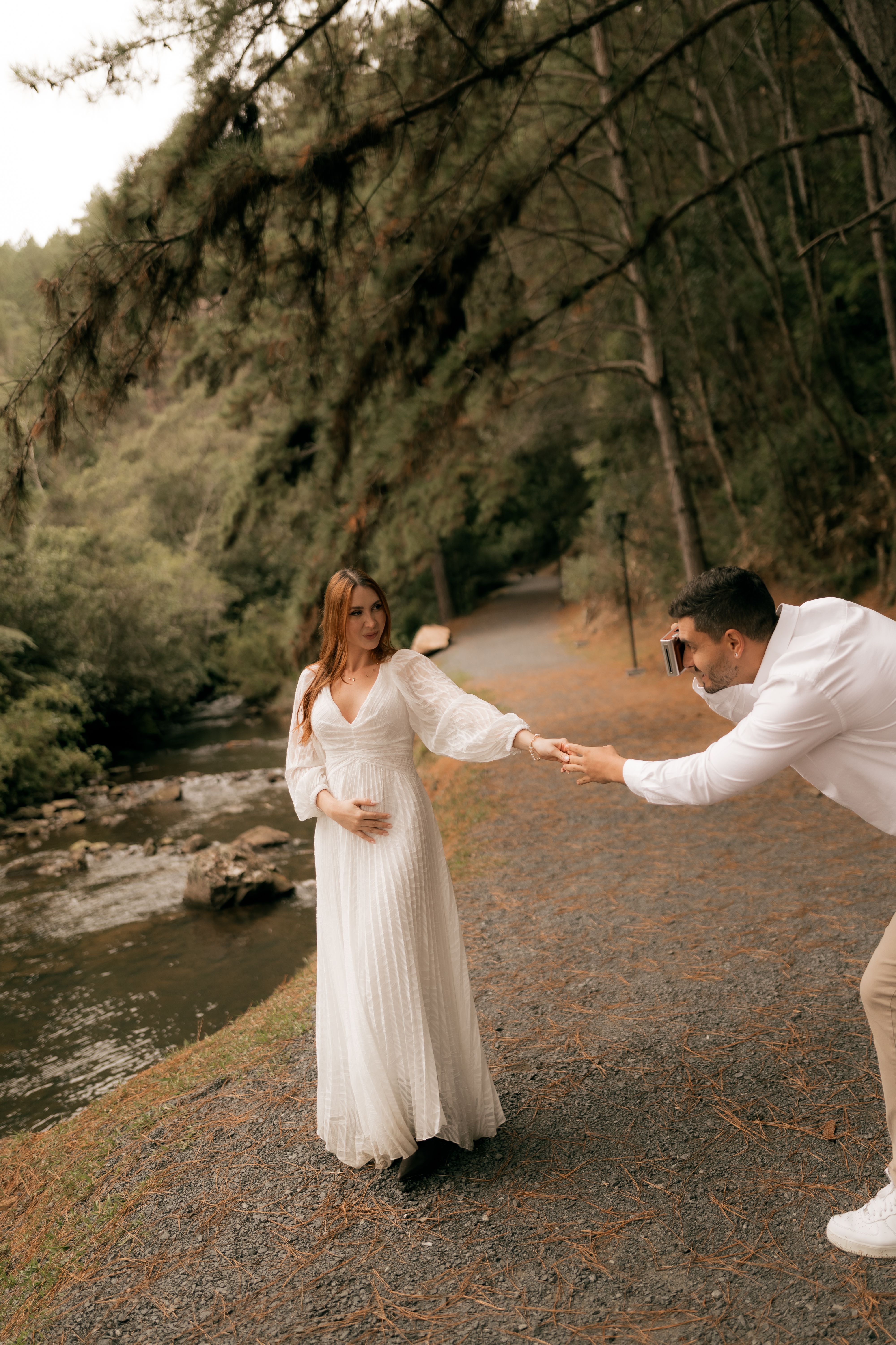 Couple enjoying a romantic photoshoot in a scenic outdoor setting by a river.